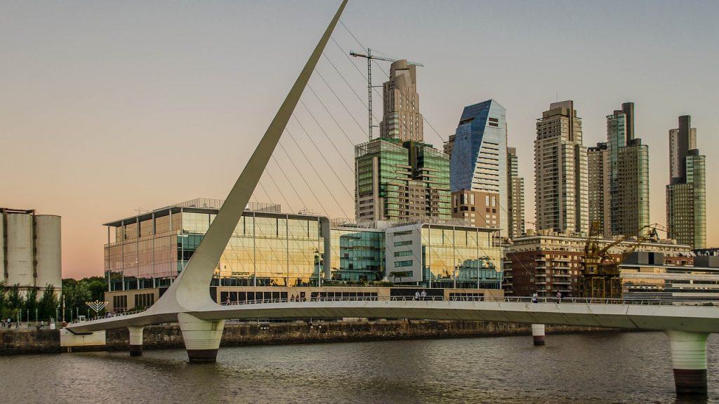 un puente sobre el agua con una ciudad al fondo. Buenos Aires, el segundo mejor destino a donde viajar en marzo..
